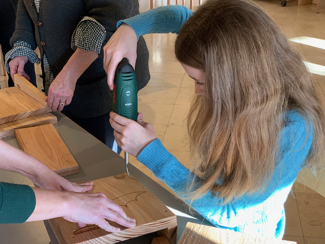 Junge Teilnehmerin beim Befestigen von zwei Teilen mit dem Akkuschrauber